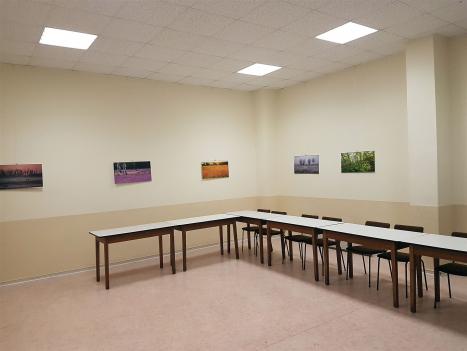 Das Bild zeigt einen leeren Raum, der wahrscheinlich als Konferenz- oder Besprechungsraum dient. Es gibt eine lange Tischreihe in U-Form mit dazugehörigen Stühlen. An den Wänden sind mehrere Landschaftsbilder angebracht. Der Raum ist hell und funktional gestaltet.